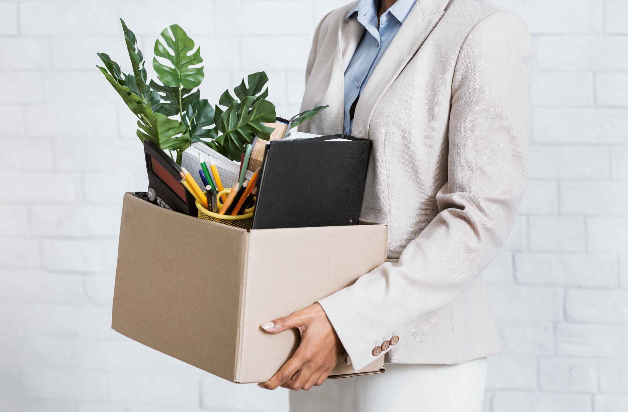 Unrecognizable black woman holding box of personal belongings, leaving office after losing her job, closeup of hands. Economic crisis and unemployment during covid-19 epidemic
